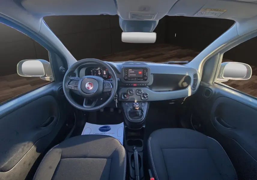 Intérieur de la Fiat Panda 2025 vue de face, tableau de bord noir avec écran multimédia et volant multifonction.