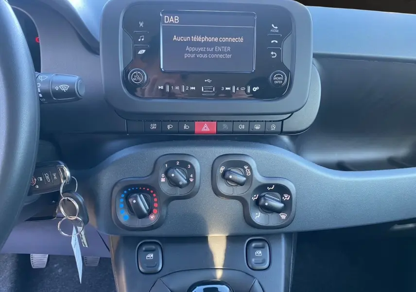 Tableau de bord et console centrale du Fiat Panda noir 2025, avec écran multimédia et commandes de climatisation visibles.