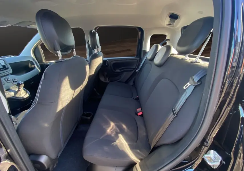 Vue intérieure côté droit montrant les sièges arrière noirs et une partie de l'avant de la Fiat Panda noire 2025.