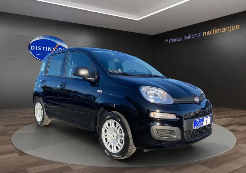 Fiat Panda noire vue en 3/4 avant droit, avec phares allumés et jantes argentées, en showroom.