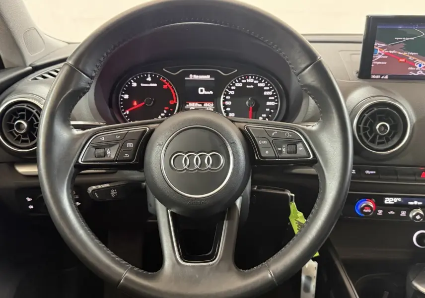 Vue centrée sur le volant cuir noir d'une Audi A3 2018 avec tableau de bord et écran de navigation visible.