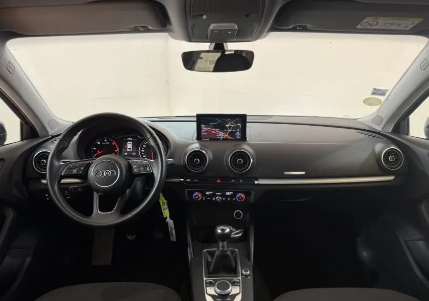 Vue intérieure frontale du tableau de bord noir de l'Audi A3 2.0 TDI 2018 avec écran central et volant cuir multifonctions.