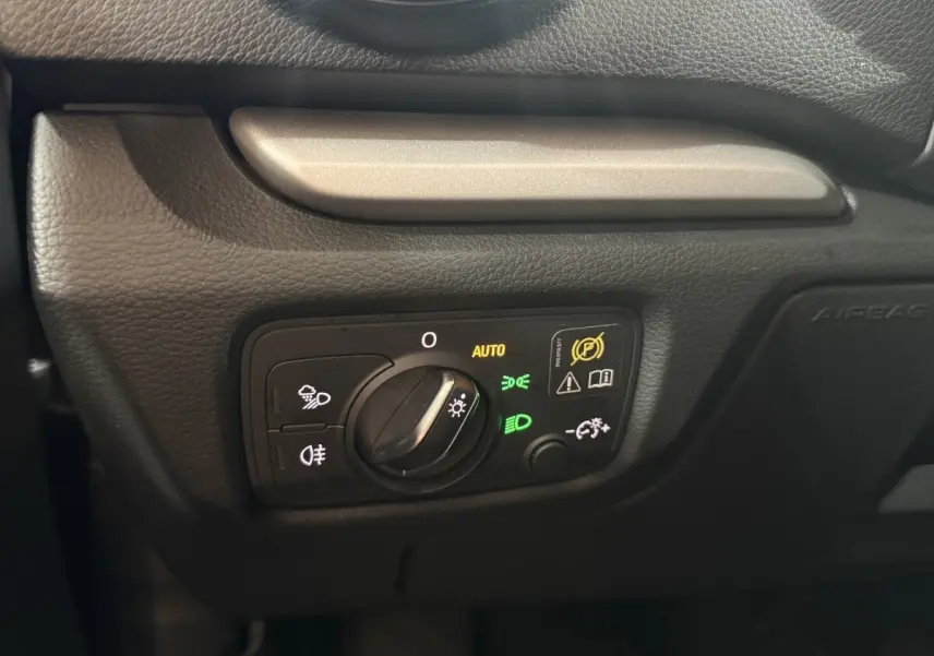 Gros plan sur la commande des phares avec réglage automatique dans l'habitacle noir de l'Audi A3 bleu 2018.