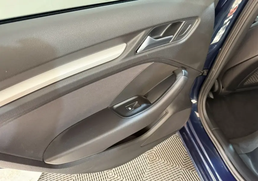 Vue rapprochée de la porte arrière droite bleu foncé d’une Audi A3 2.0 TDI 2018 avec accoudoir et commande de lève-vitre.