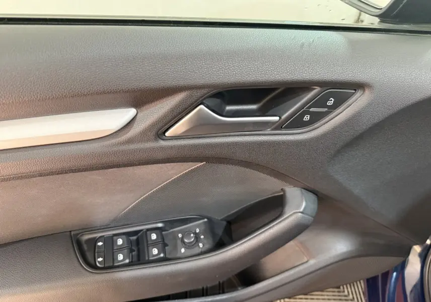 Vue rapprochée de la porte avant gauche bleu foncé de l'Audi A3 2.0 TDI 2018 avec commandes de vitres et serrure.