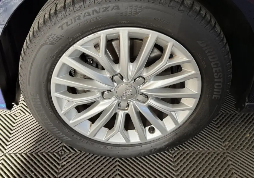 Gros plan sur la jante alliage argentée et pneu Bridgestone d'une Audi A3 bleu, côté avant gauche.