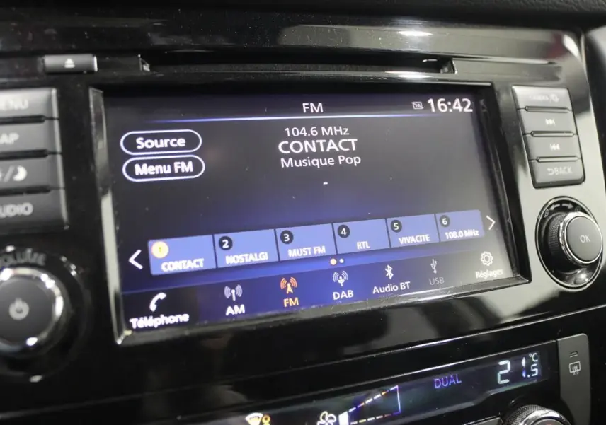 Gros plan sur l'écran multimédia et la console centrale du Nissan X-Trail 1.7 D 150, affichant la radio FM et la climatisation digitale.