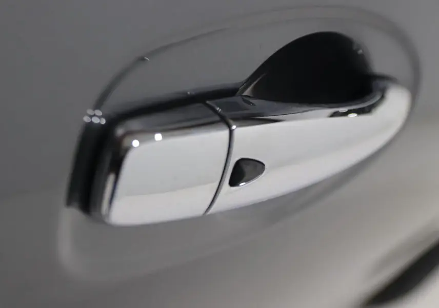 Poignée de porte chromée en gros plan sur Nissan X-TRAIL gris métallisé, côté droit du véhicule.