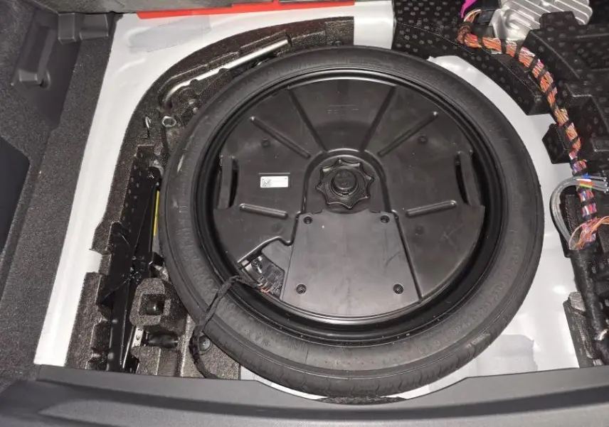 Vue rapprochée de la roue de secours compacte noire dans le coffre blanc du CUPRA Formentor 2025.