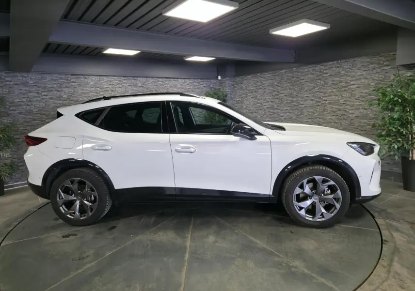 Vue de profil côté gauche d’un CUPRA Formentor blanc avec jantes alliage 18 pouces et bas de caisse noirs.