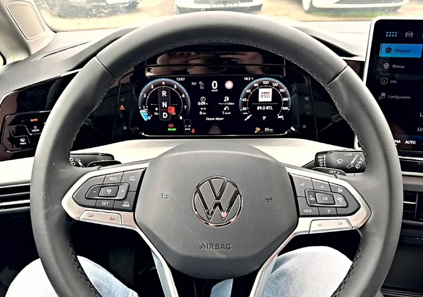 Vue rapprochée du volant noir de la Volkswagen Golf 2026 avec tableau de bord numérique et commandes intégrées.