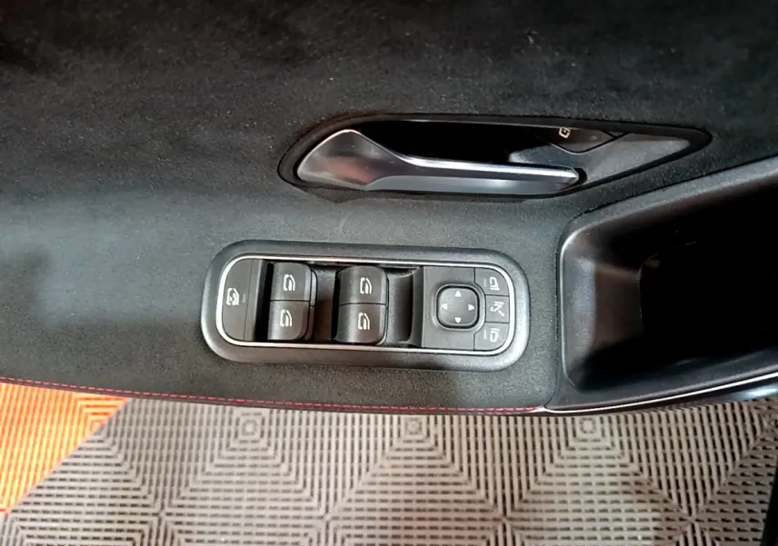 Commande des vitres et rétroviseurs sur la porte côté gauche d'une Mercedes Classe A 180 AMG Line noire, intérieur noir avec surpiqûres rouges.