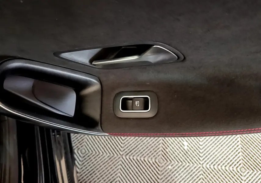 Détail de la poignée intérieure noire avec bouton de verrouillage sur la porte côté gauche d'une Mercedes Classe A 180 AMG Line noire.