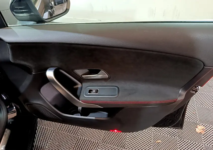 Intérieur côté gauche de porte Mercedes Classe A 180 AMG Line noire avec surpiqûres rouges et poignée alu.