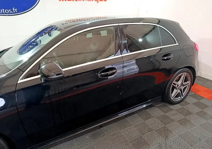 Profil côté gauche d'une Mercedes Classe A 180 AMG Line noire, soulignant ses jantes sport et ses lignes élégantes.