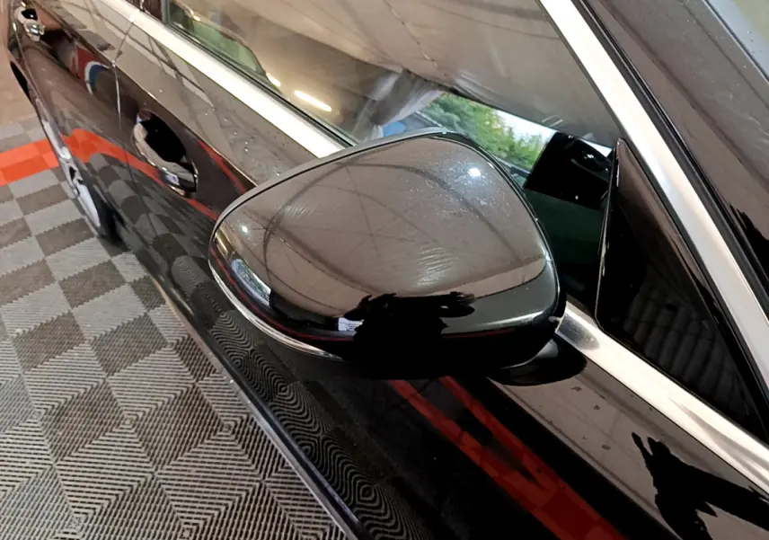 Gros plan sur le rétroviseur côté gauche noir brillant d'une Mercedes Classe A A 180 AMG Line noire, vue latérale.