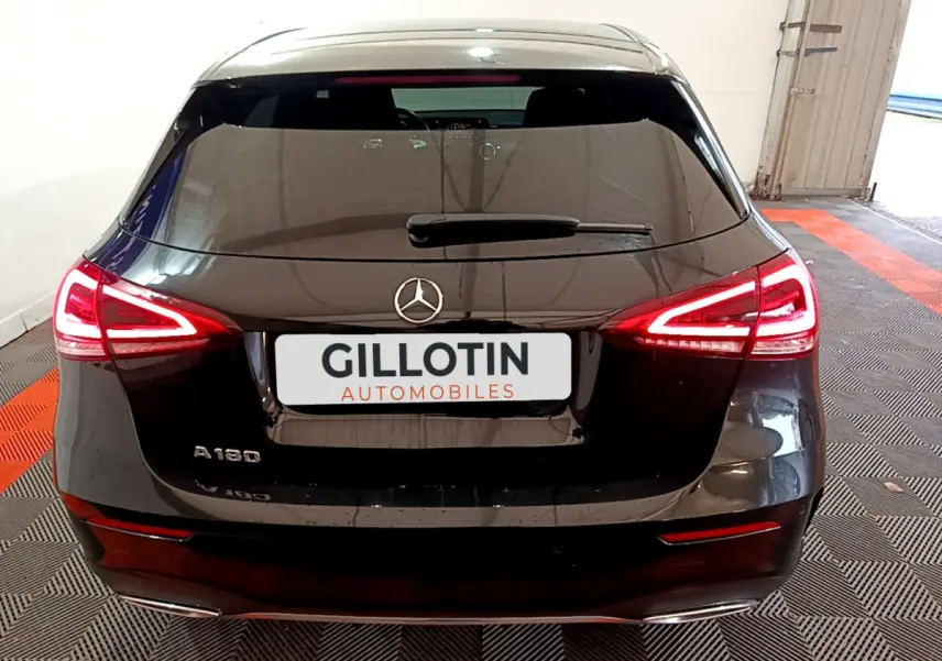 Vue arrière d'une Mercedes Classe A 180 AMG Line noire avec feux LED allumés dans un garage.