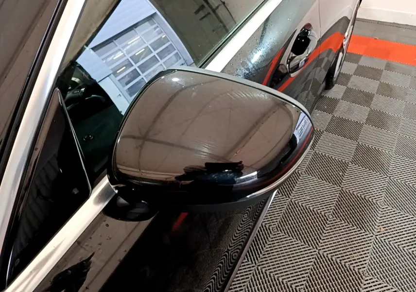 Rétroviseur côté gauche noir brillant de la Mercedes Classe A 180 AMG Line 2019 vue en gros plan sur fond de sol carrelé.