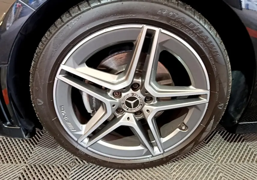 Gros plan sur la jante AMG en alliage argentée d'une Mercedes Classe A 180 AMG Line noire, côté gauche.