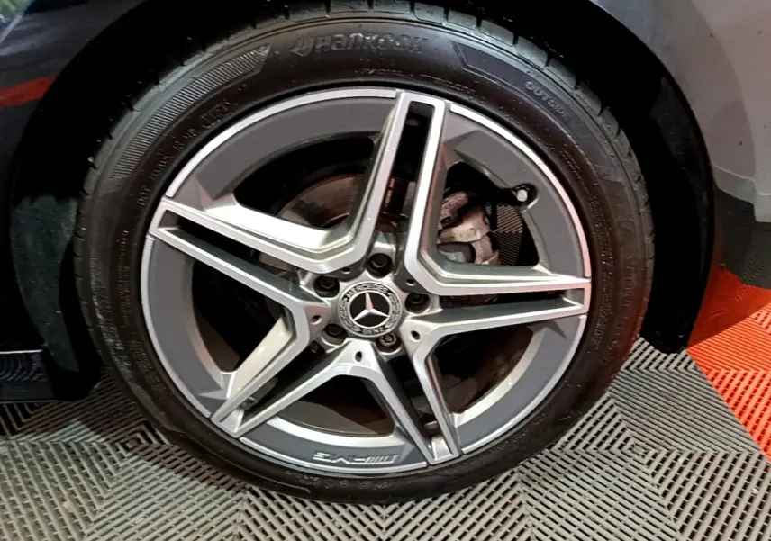 Gros plan sur la jante AMG en alliage gris avec logo Mercedes sur la roue avant gauche d'une Classe A noire.