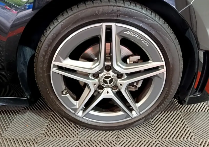 Gros plan sur la roue avant droite noire d'une Mercedes Classe A 180 AMG Line avec jante AMG argentée.