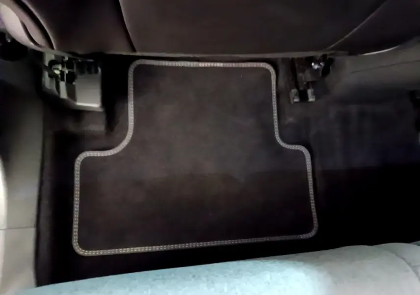 Vue rapprochée du tapis de sol noir avec surpiqûres claires à l'avant droit d'un Citroën C5 Aircross gris foncé.