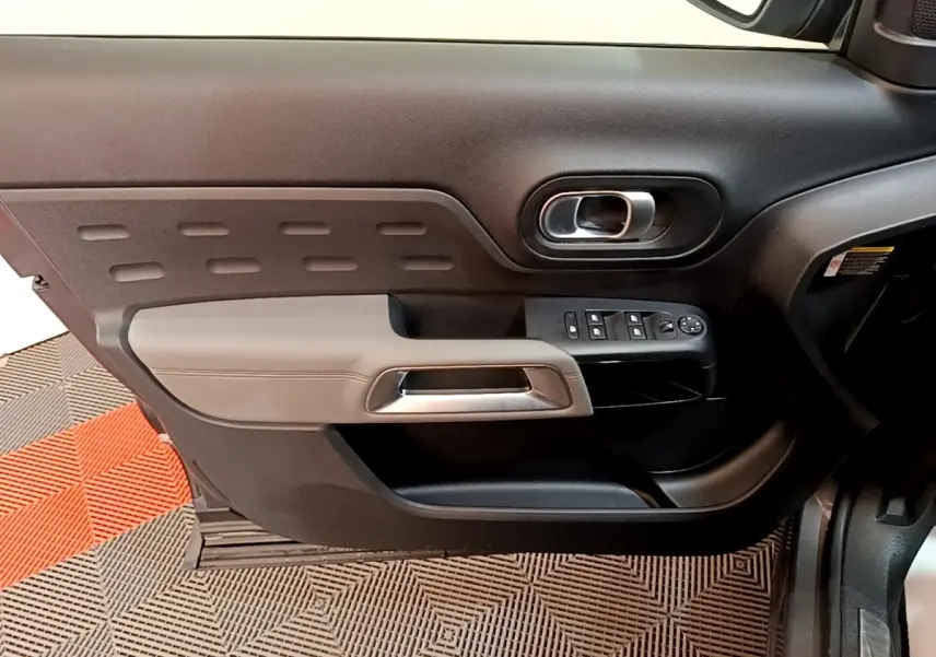 Vue intérieure côté gauche de la porte avant d'une Citroën C5 Aircross 2020 avec commandes de vitres et poignée argentée.