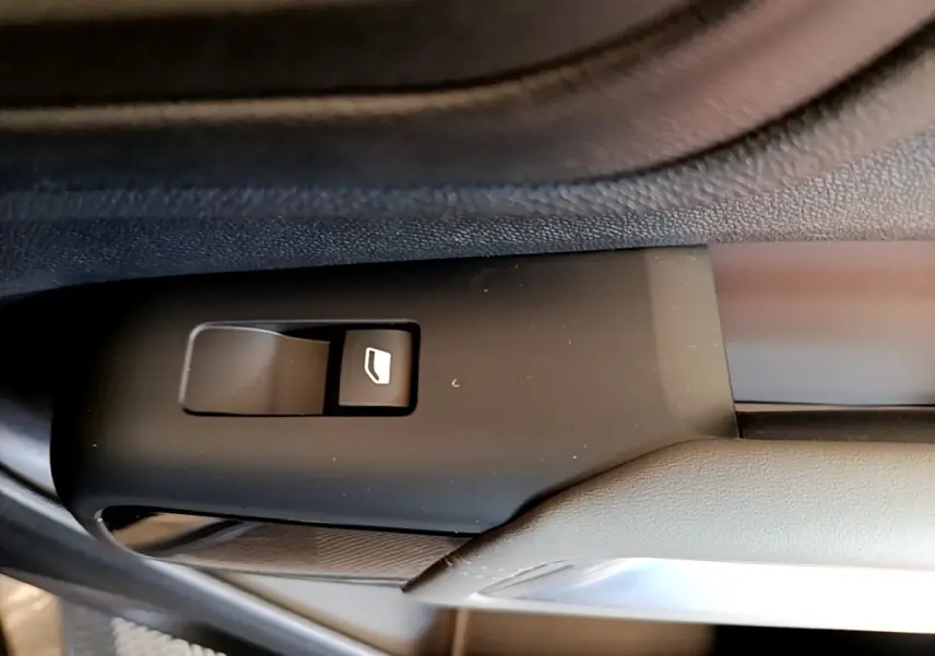 Gros plan sur l'interrupteur de lève-vitre côté conducteur dans l'habitacle noir du Citroën C5 Aircross gris foncé.