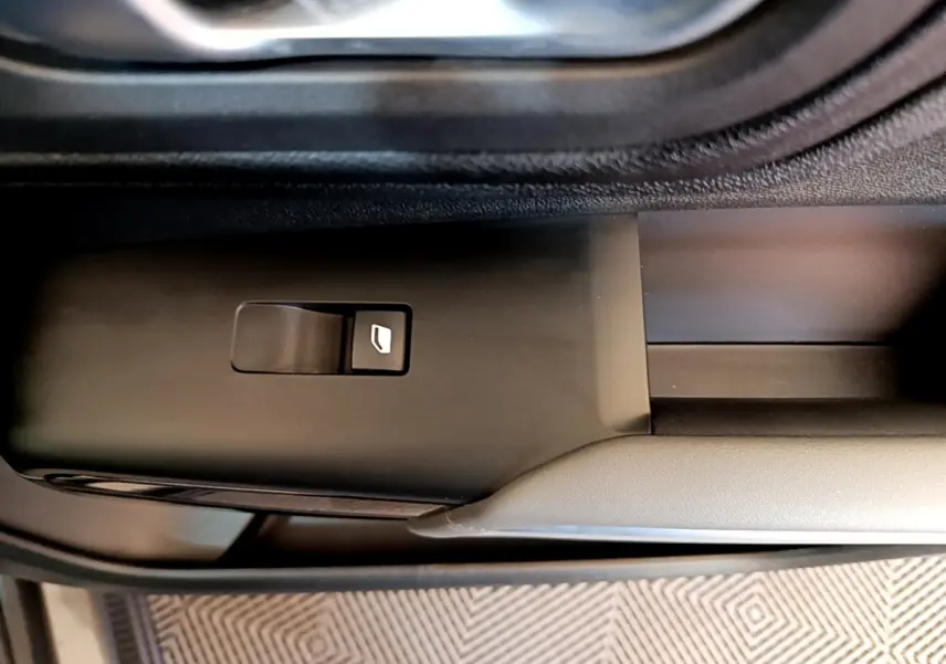 Gros plan sur le bouton de commande de la vitre électrique côté conducteur du Citroën C5 Aircross gris foncé.