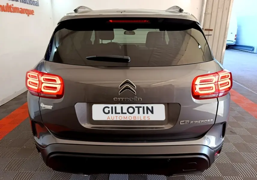 Vue arrière d'un Citroën C5 Aircross gris foncé avec feux arrière LED allumés dans un garage.