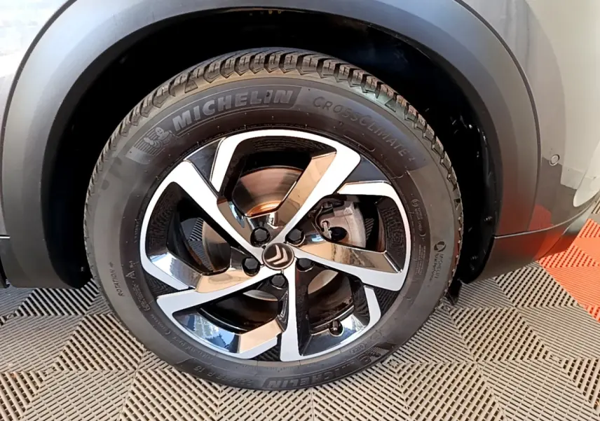 Gros plan sur la roue arrière droite d’un Citroën C5 Aircross gris foncé, avec pneu Michelin et passage de roue noir mat.