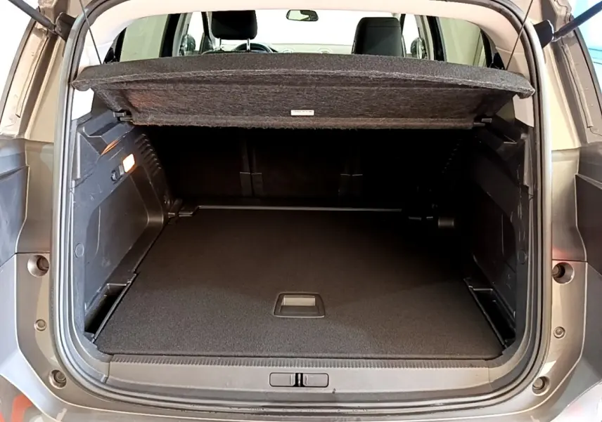 Coffre ouvert vu de l'arrière d'un Citroën C5 Aircross gris foncé, avec cache-bagages relevé et intérieur spacieux.
