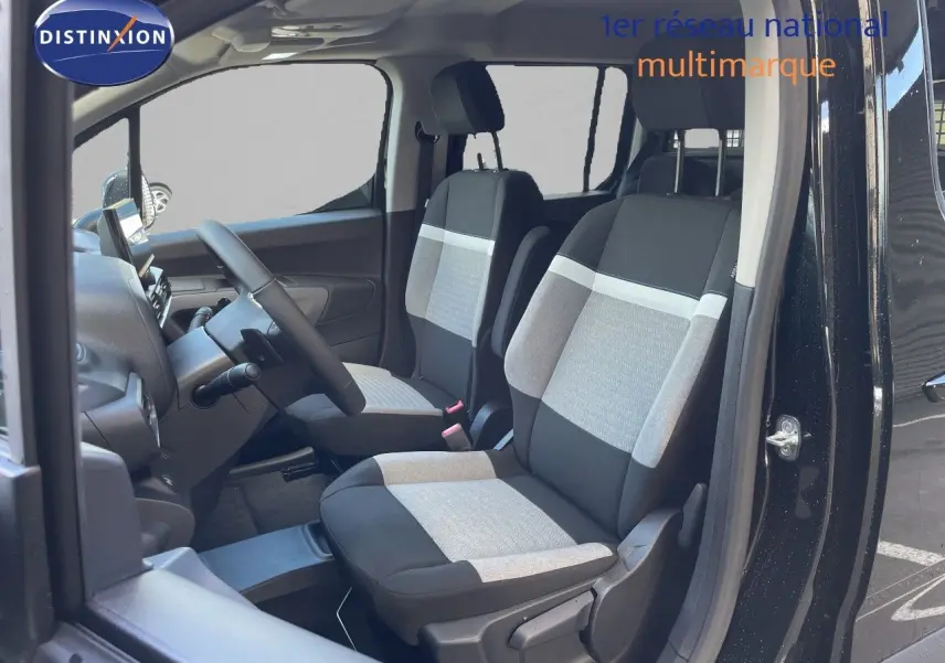 Vue intérieure côté conducteur du Citroën Berlingo noir Perla Nera, montrant les sièges tissu bicolores et le volant multifonction.