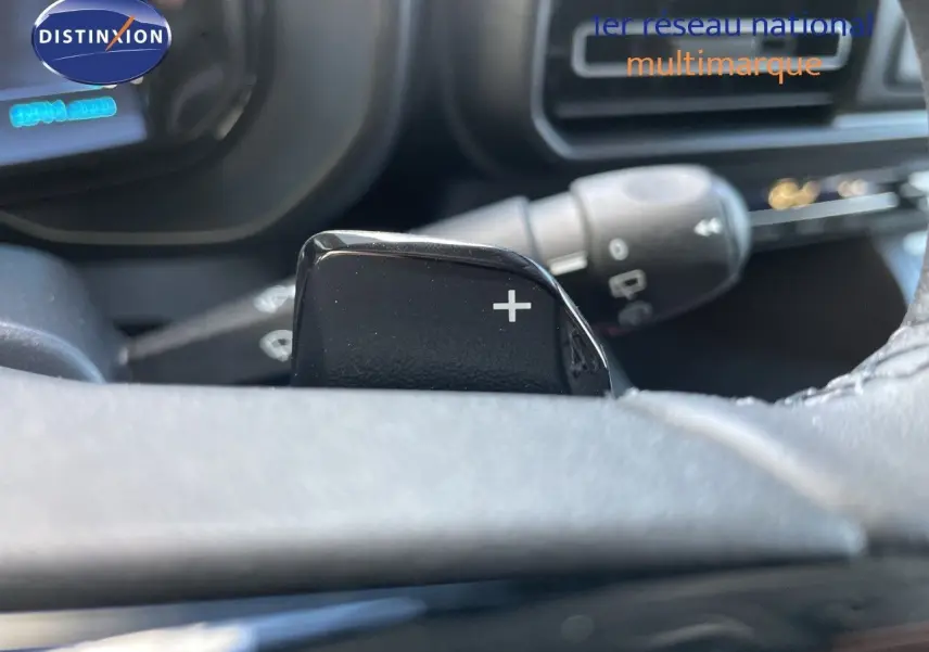 Gros plan sur la palette de changement de vitesse "+" au volant d'un Citroën Berlingo noir Perla Nera, intérieur sombre.