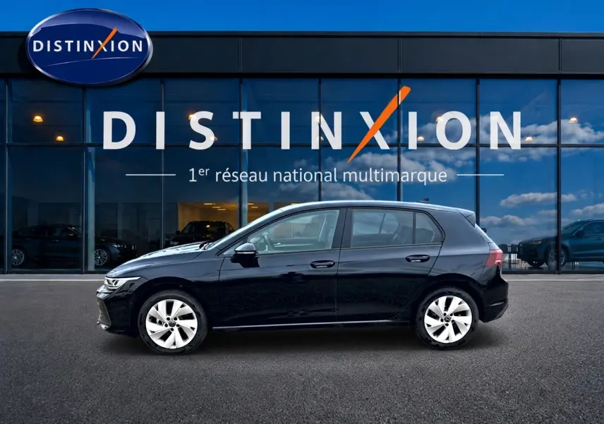 Volkswagen Golf 2026 noire vue de profil côté gauche devant une vitrine avec logo Distinxion.