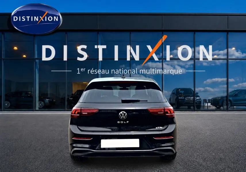 Vue arrière d'une Volkswagen Golf noire 2026 garée devant une vitrine avec logo Distinxion en arrière-plan.