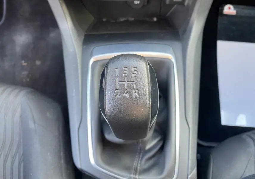 Le levier de vitesses manuel noir de la Peugeot 308 1.6 BlueHDi vu de dessus au centre de la console.