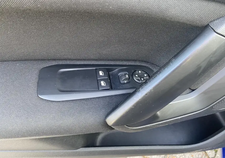 Gros plan sur les commandes de lève-vitres et rétroviseurs côté conducteur d'une Peugeot 308 bleu foncé de 2017.