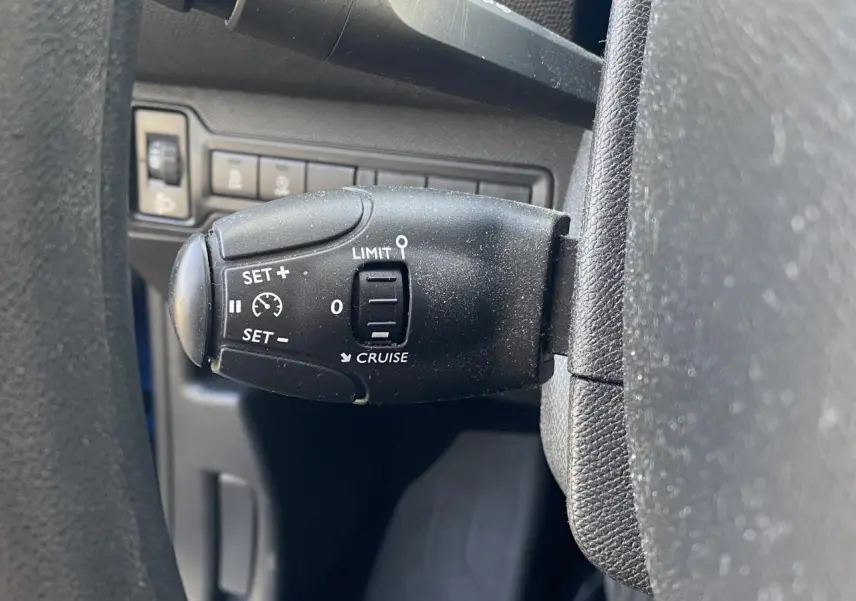 Gros plan sur la commande du régulateur de vitesse au volant d'une Peugeot 308 bleu foncé de 2017.