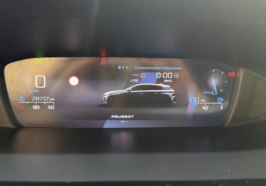 Affichage numérique du tableau de bord de la Peugeot 308 bleu, montrant silhouette du véhicule et données de consommation instantanée.