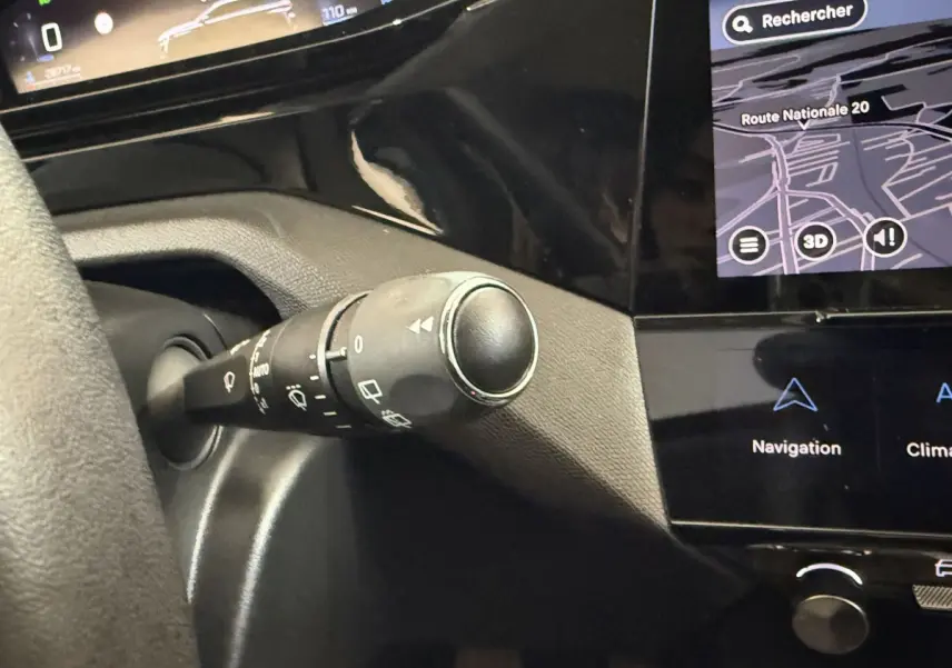 Gros plan sur la commande d'essuie-glace à gauche du volant dans l'habitacle noir de la Peugeot 308 2023.