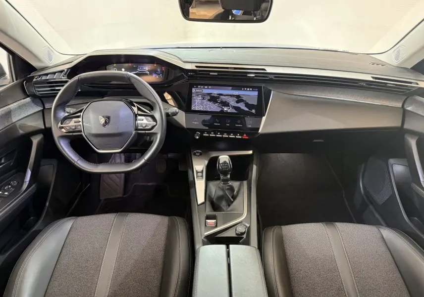 Vue intérieure avant de la Peugeot 308 PureTech 130 bleu, avec tableau de bord digital et volant cuir multifonctions.