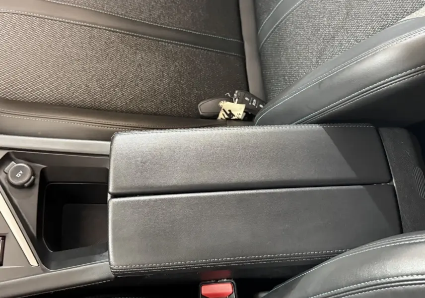 Vue rapprochée de l'accoudoir central noir et des sièges en tissu bleu foncé de la Peugeot 308 2023.