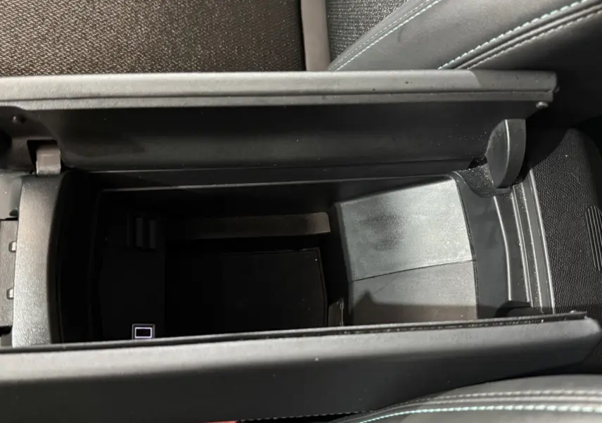 Vue plongeante sur le rangement central ouvert de la Peugeot 308 bleu, avec port USB visible à l'intérieur.