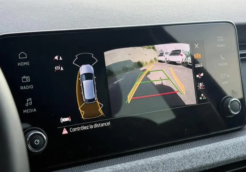 Écran intérieur affichant la caméra de recul et l’aide au stationnement d’une Skoda Scala noire Magic Perle.