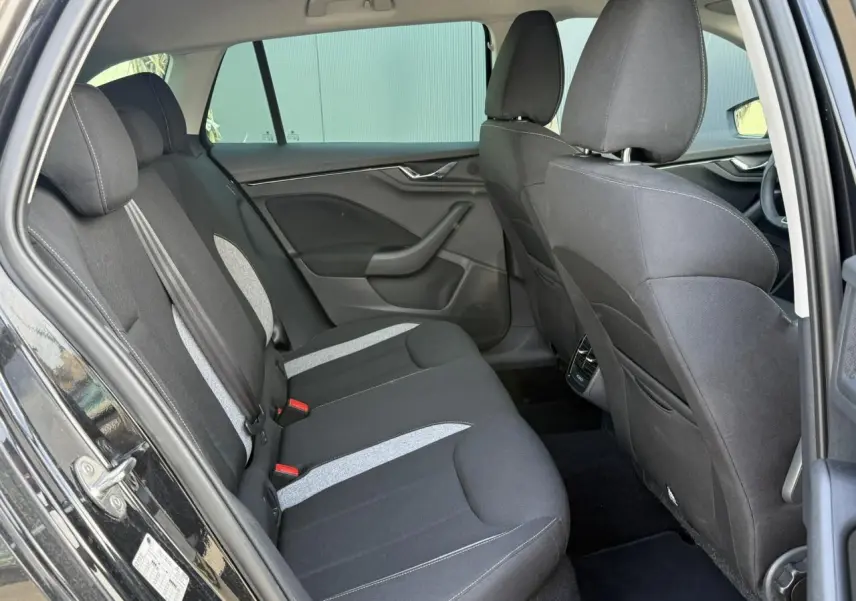 Vue côté gauche de l'habitacle arrière d'une Skoda Scala noir Magic Perle avec sièges tissu bicolores et surpiqûres claires.