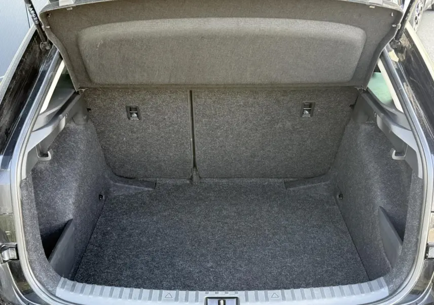 Coffre ouvert vu de l'arrière d'une Skoda Scala TSI 116 DSG7 noir Magic Perle, intérieur en moquette grise.
