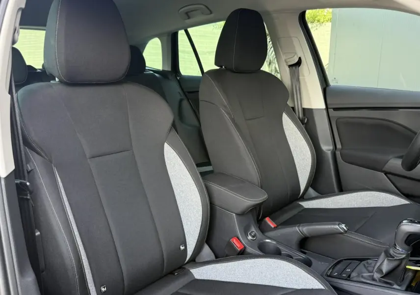 Vue intérieure des sièges avant bi-ton gris et noir de la Skoda Scala TSI 116 DSG7 avec accoudoir central et levier de vitesse.
