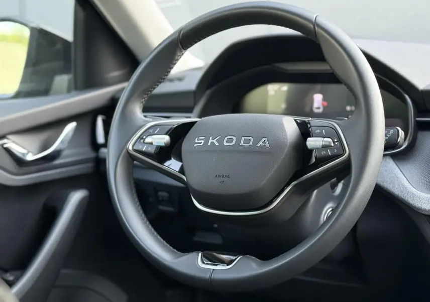 Gros plan sur le volant cuir multifonctions Skoda noir à deux branches dans l'habitacle côté conducteur.