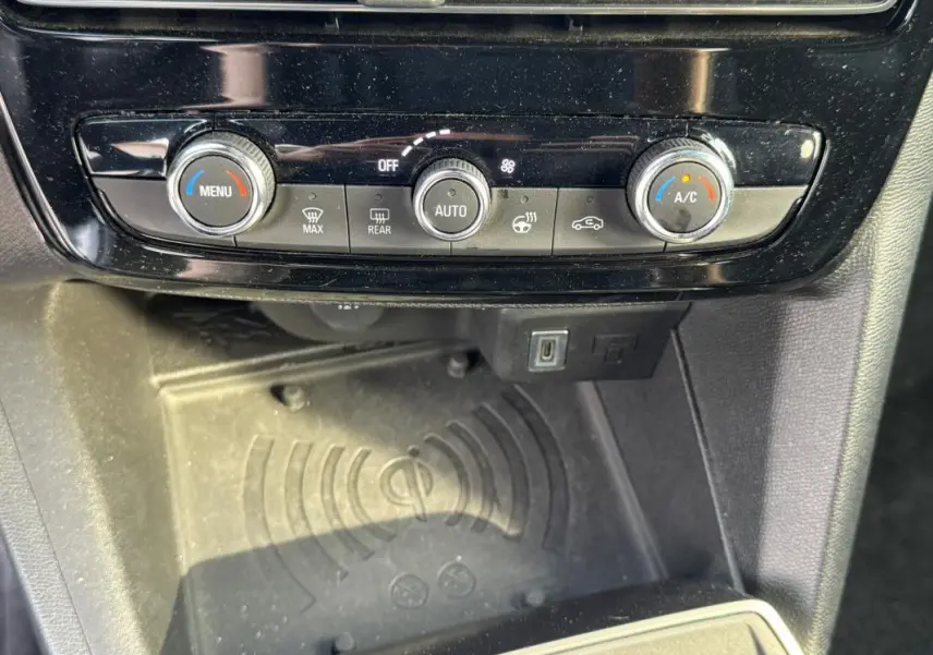 Gros plan sur la console centrale de l'Opel Mokka électrique 2025, montrant les commandes de climatisation et un espace de recharge sans fil.